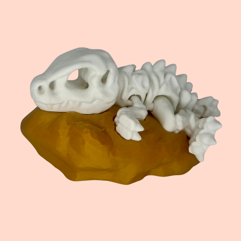 White ceramic lizard on a brown rock against a pink background