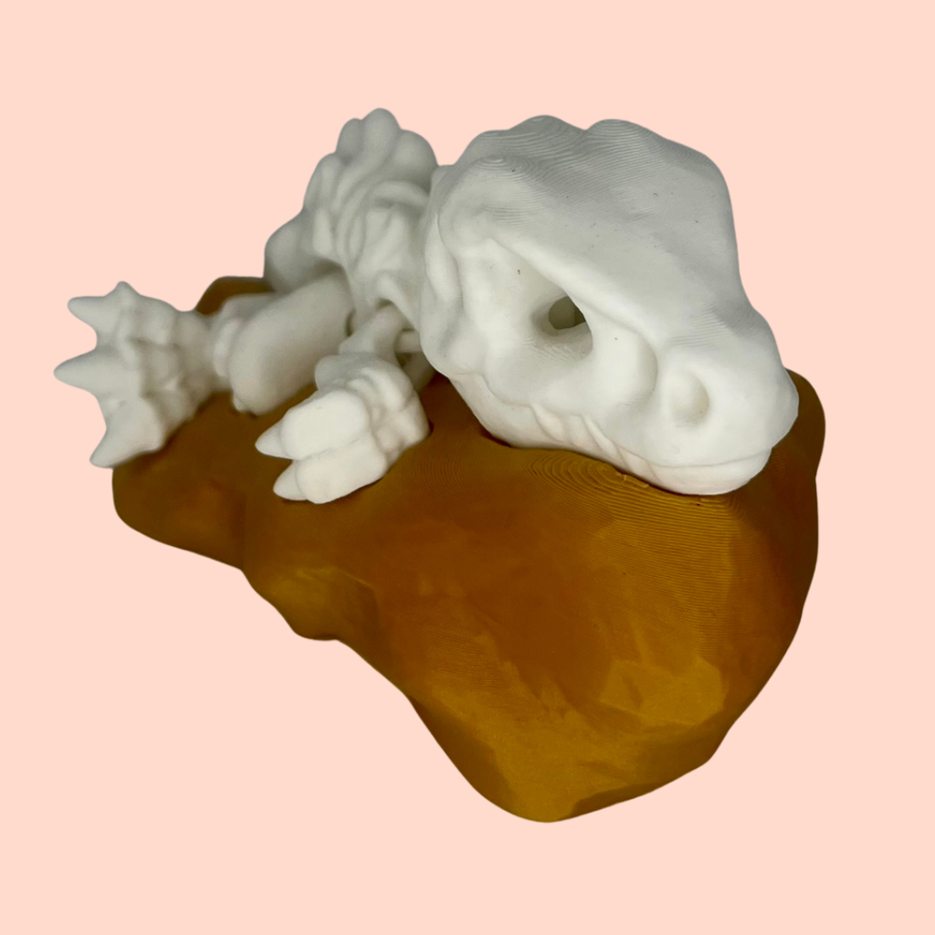 White ceramic lizard sculpture on a brown base against a pink background