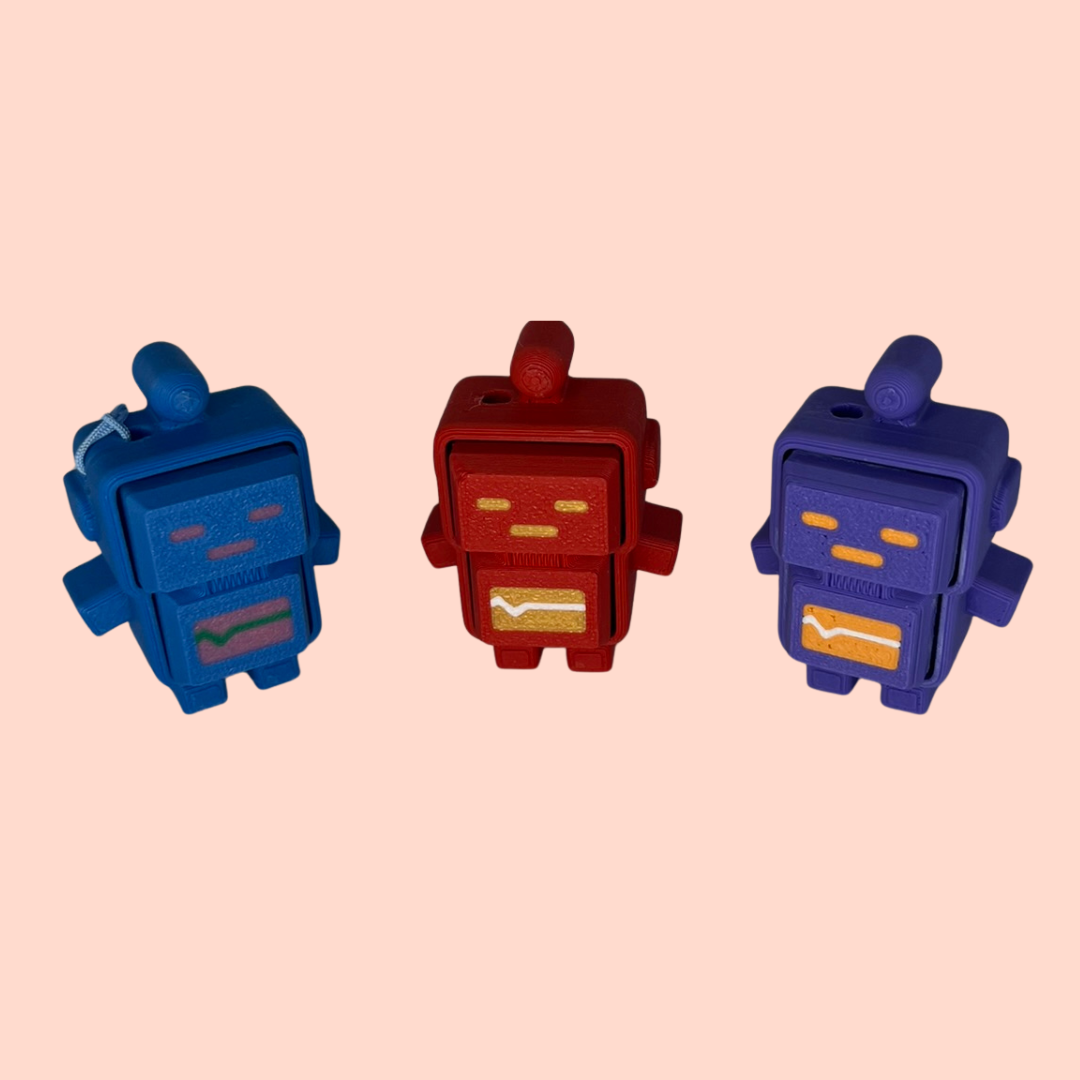 Three robot-shaped objects in blue, red, and purple on a pink background