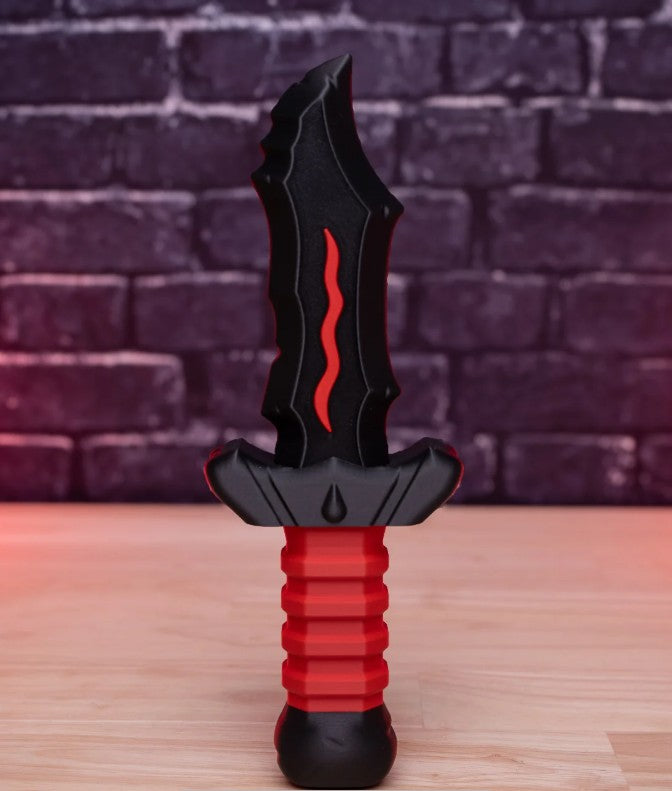 Black and red toy dagger on a wooden surface with a brick wall background