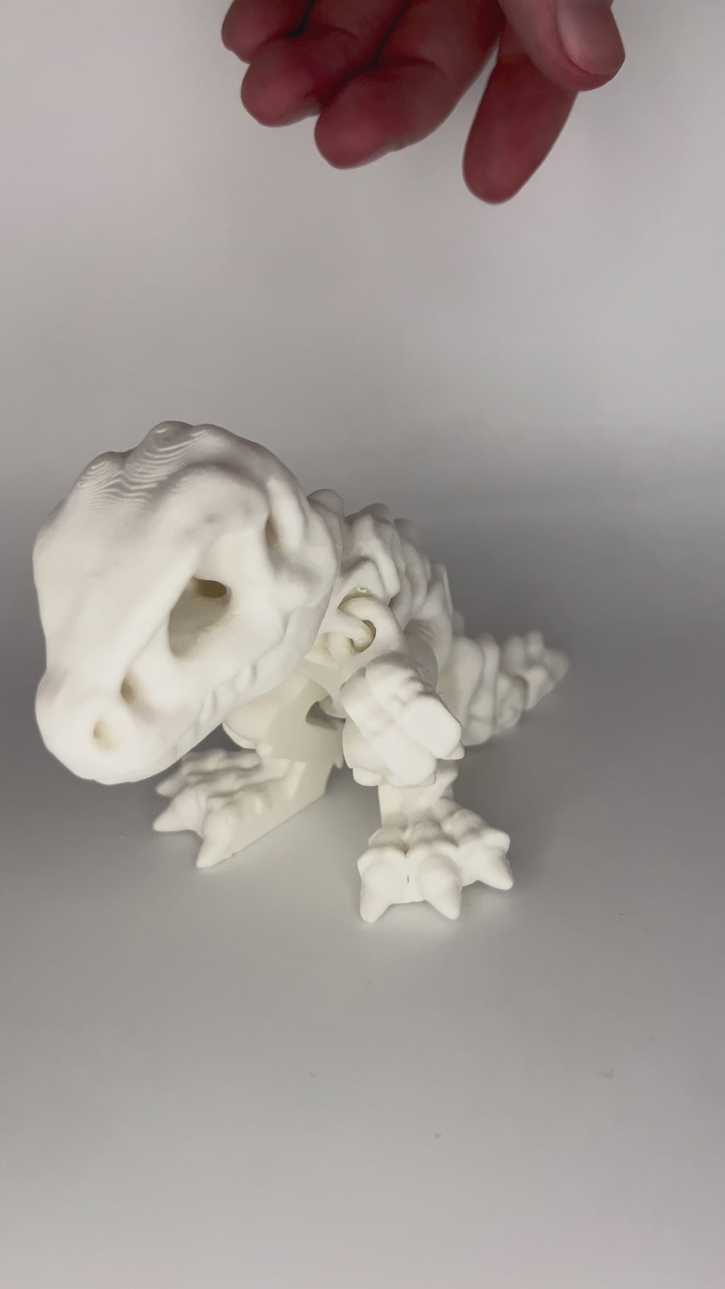 hand playing with white dinosaur articulated figure moving side to side