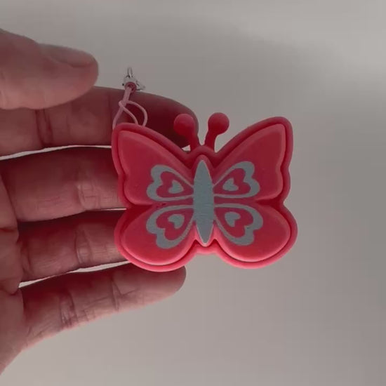 A hand holding a pink butterfly fidget clicker