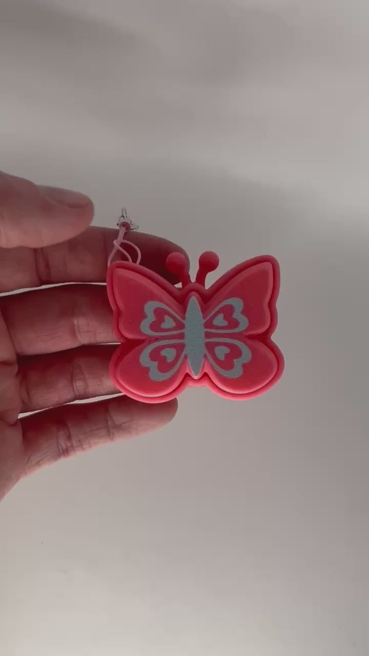 A hand holding a pink butterfly fidget clicker