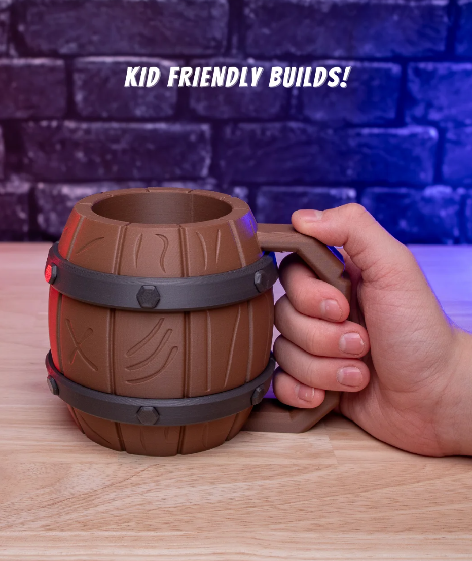 Hand holding a brown barrel-shaped mug with 'KID FRIENDLY BUILDS!' text above on a wooden surface.